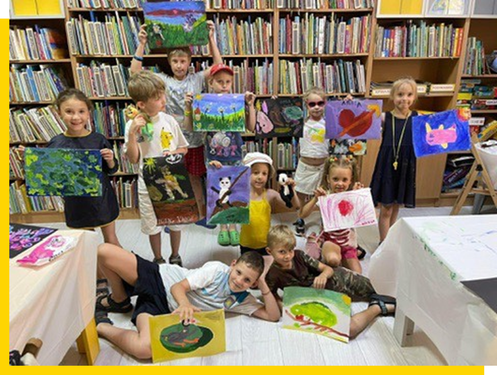 A group of children holding up their paintings.